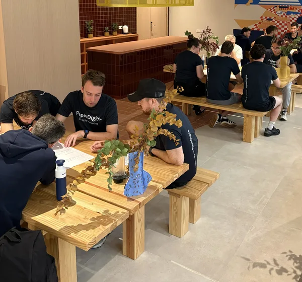 Het team van PaperDigits aan het werk aan lange tafels
